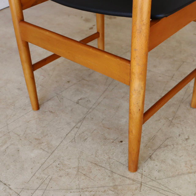 Mid-century British vintage teak dining chair leg with visible wood grain and black seat upholstery.