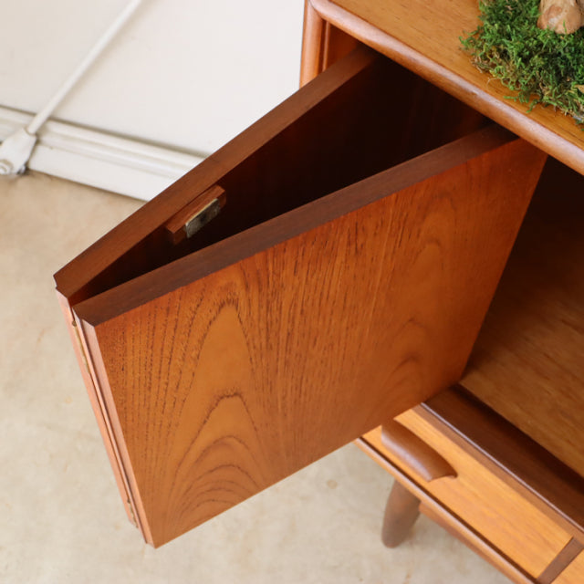 Vintage teak G-Plan sideboard door open, showcasing rich wood grain and smooth mid-century British design with tapered legs.