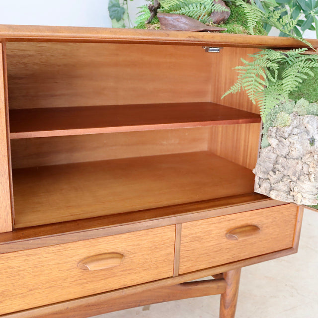 Vintage mid-century British teak G-PLAN sideboard with rich wood grain, open cabinet, two drawers, and tapered legs.