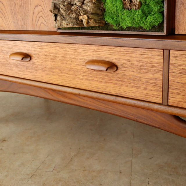 Vintage British G-Plan teak sideboard drawer with smooth wood grain and mid-century curved leg detail.