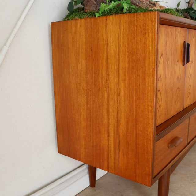 Vintage teak G-Plan sideboard with rich wood grain, slender tapered legs, and mid-century British design from Denmark.
