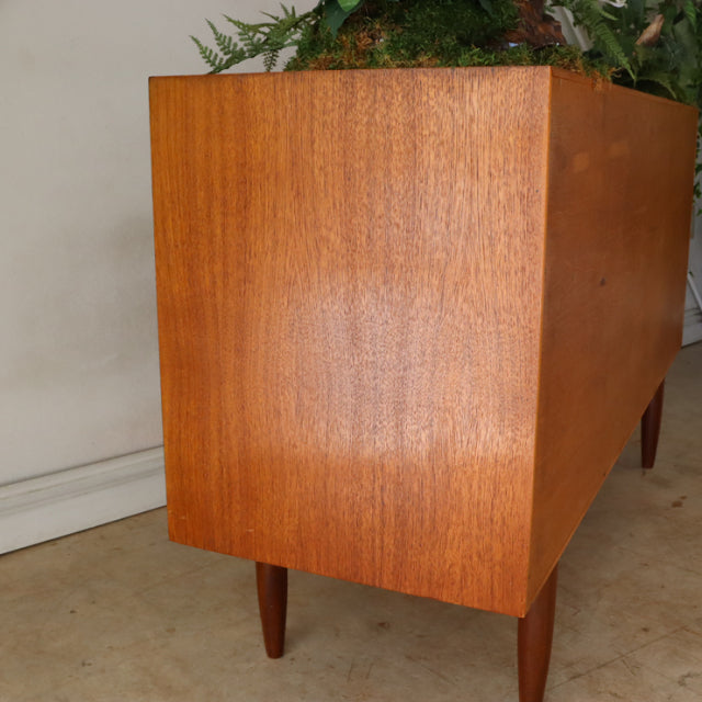 Vintage teak G-Plan sideboard in British mid-century style, smooth wood grain, tapered legs, Danish design influence.