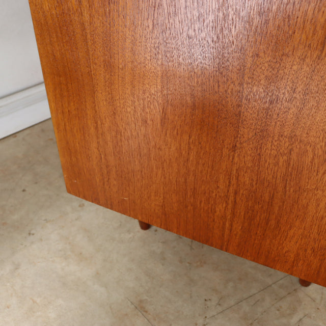 Vintage British mid-century teak sideboard leg detail showing warm wood grain and tapered design.