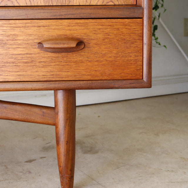 Vintage teak G-Plan sideboard leg and drawer with smooth wood grain, mid-century British design influenced by Danish style.