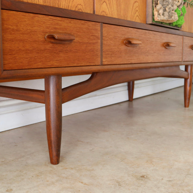 Vintage British mid-century teak G-Plan sideboard with visible wood grain, tapered legs, and sleek drawer handles.