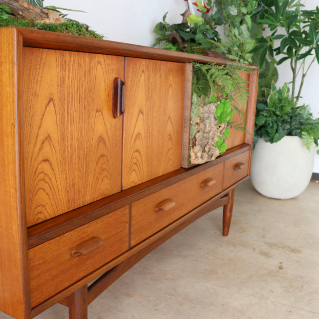 Vintage teak G-Plan sideboard with rich wood grain, mid-century British design, slender tapered legs, and three lower drawers.