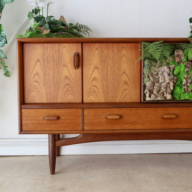Vintage British G-Plan teak sideboard with mid-century Denmark design, showcasing wood grain, tapered legs, and three.