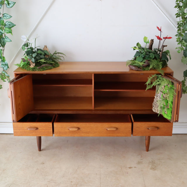 Vintage teak G-Plan sideboard with mid-century British design, open shelving, three drawers, and tapered legs.