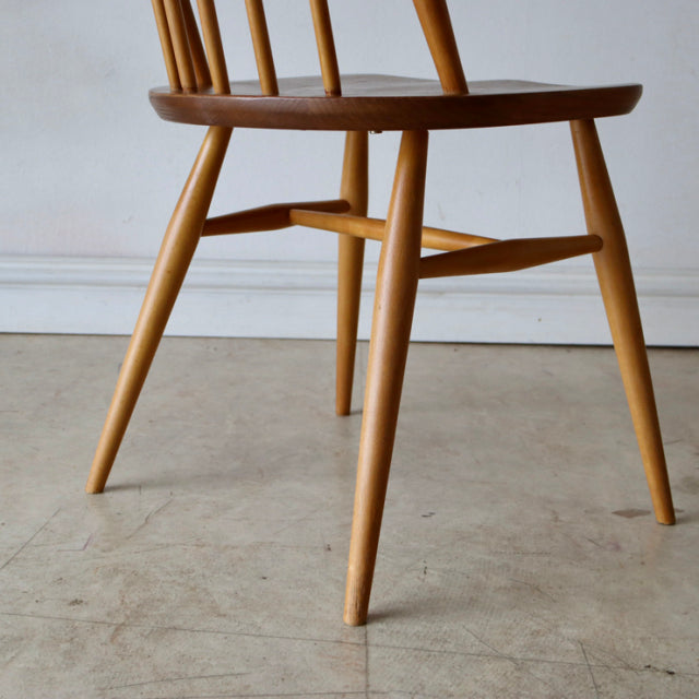 Mid-century British Ercol Quaker chair in natural teak with smooth tapered legs and visible wood grain.