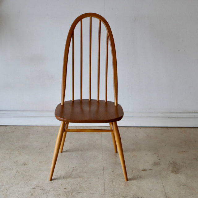 Vintage British mid-century Ercol Quaker chair in natural teak with arched spindle back and tapered legs.