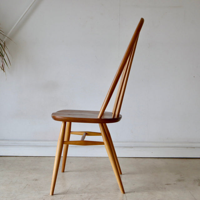 Vintage British Ercol Quaker dining chair in natural teak with slender tapered legs and high spindle back, mid-century.