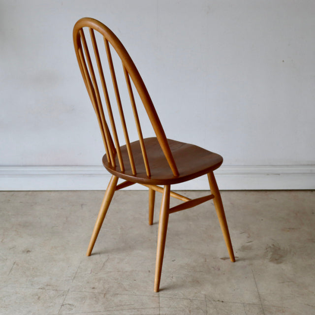 Mid-century British ERCOL vintage dining chair in natural teak with curved spindle back and tapered legs.