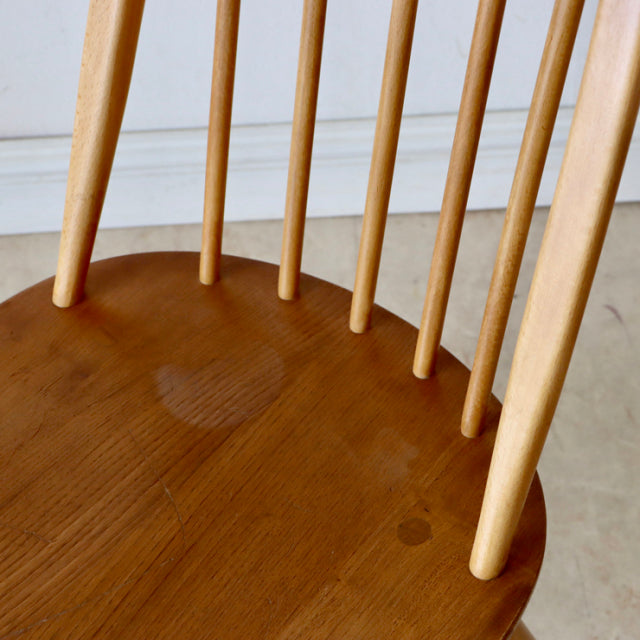 Vintage British Ercol Quaker dining chair in natural teak with slender mid-century spindle back and smooth curved seat.