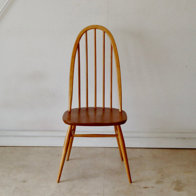 Vintage British Ercol Quaker chair in natural teak with mid-century arched back and slender spindle legs.