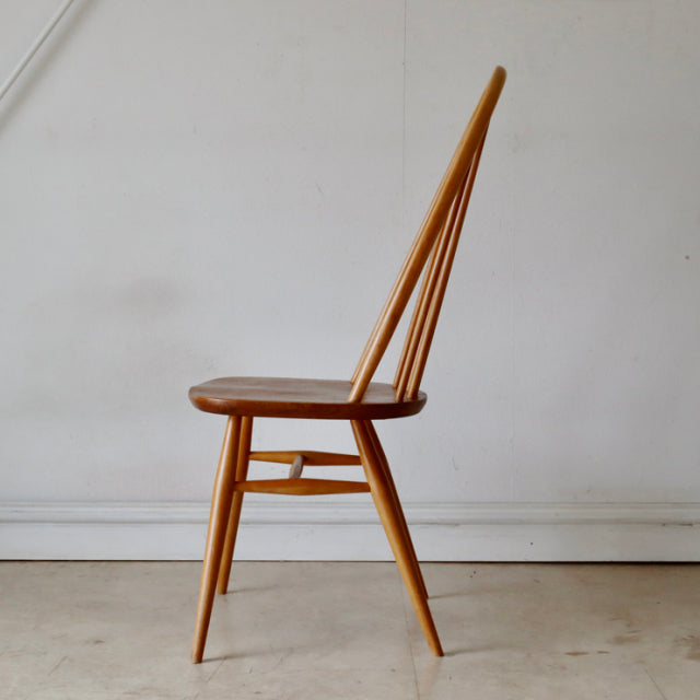 Vintage British mid-century Ercol Quaker chair in natural teak with slender spindle back and angled legs.