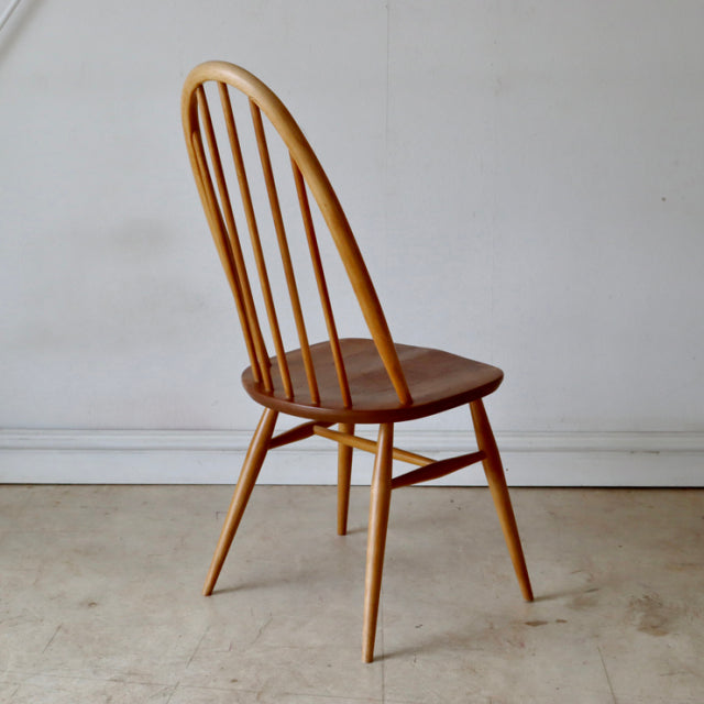 Vintage mid-century British ERCOL Quaker chair in natural teak with curved spindle back and tapered legs.