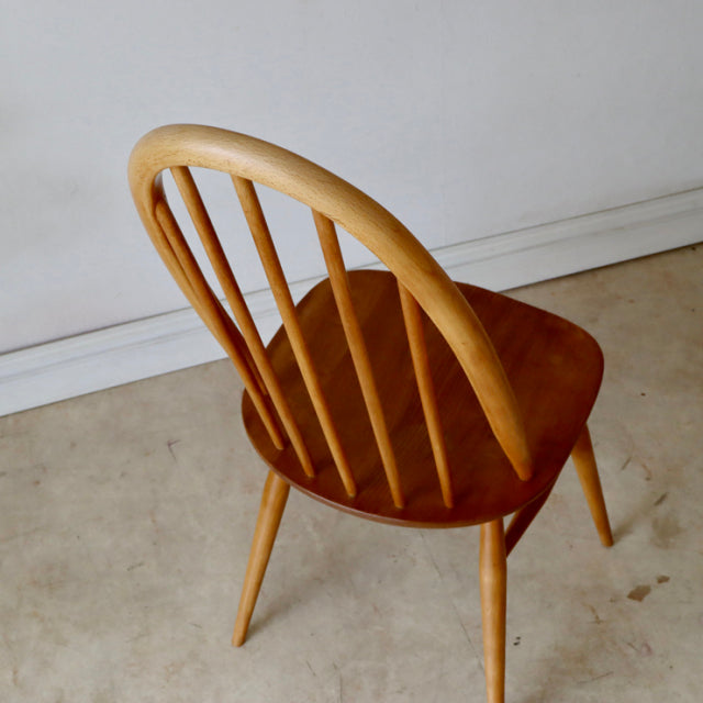 Vintage British Ercol Quaker chair in natural teak with curved spindle back and tapered legs, mid-century Danish design.