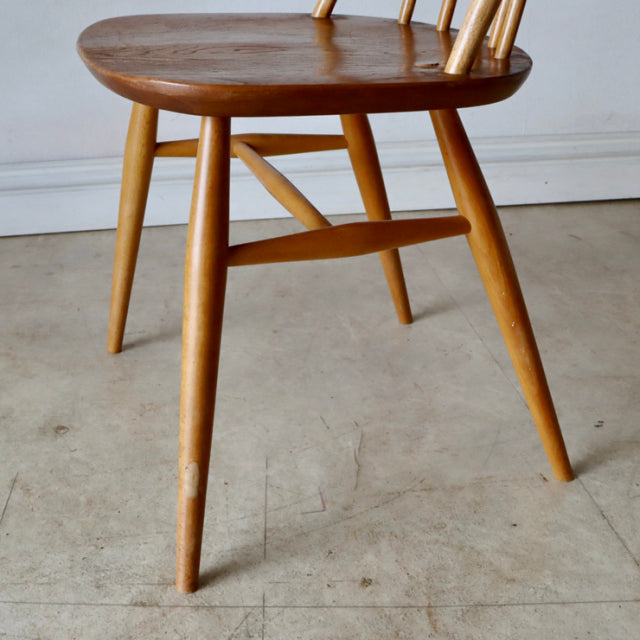Vintage British Ercol mid-century teak dining chair with spindle back and tapered legs, natural finish showing wood grain.