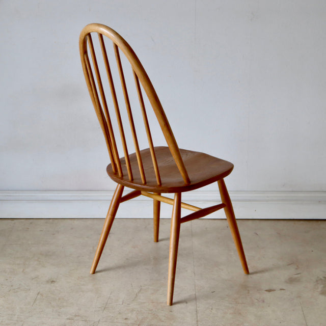 Vintage British Ercol Quaker dining chair in natural teak with curved spindle back and tapered legs, mid-century.