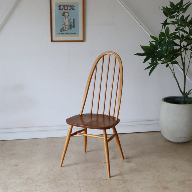 Vintage British mid-century Ercol Quaker chair in natural teak with curved spindle back and rounded seat.