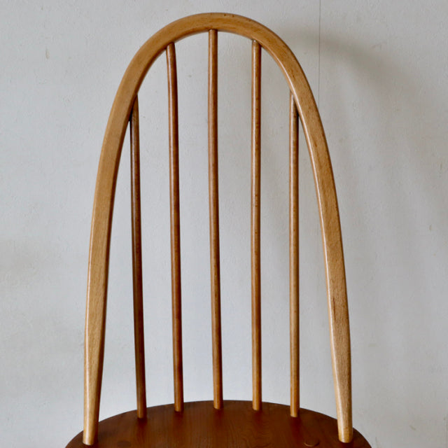 Vintage British mid-century Ercol Quaker chair in natural teak with curved spindle back and smooth wood grain.