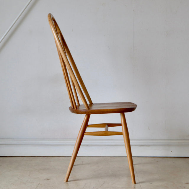 Mid-century British Ercol Quaker chair in natural teak with slender spindled backrest and angled legs showcasing vintage.