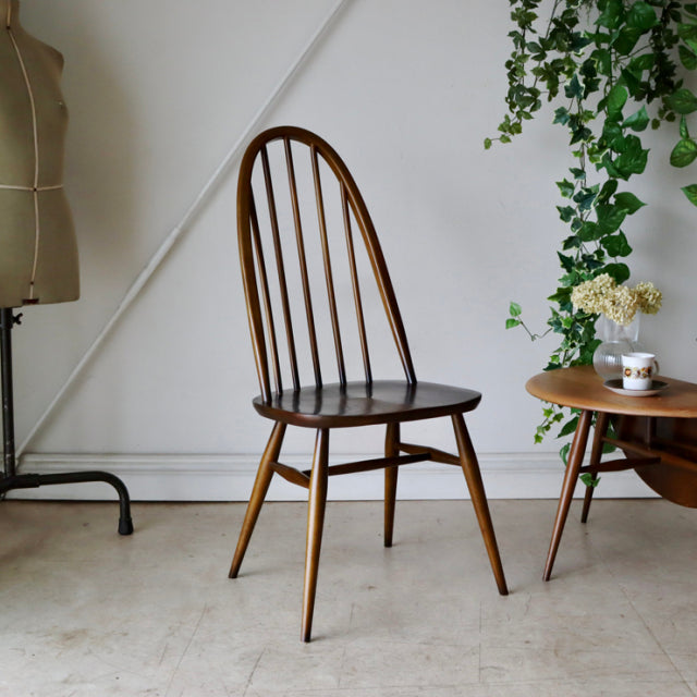 Vintage British Ercol Quaker chair in warm teak with curved spindle back and tapered legs, mid-century Danish-inspired design.
