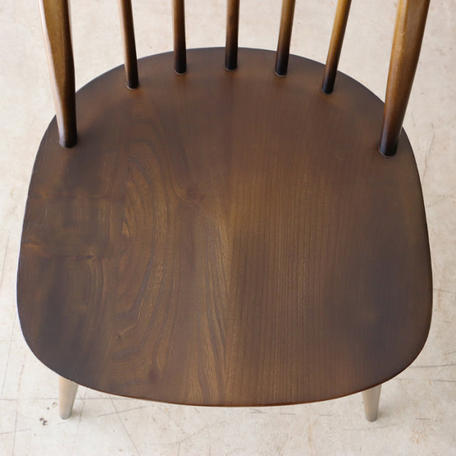 Vintage British mid-century Ercol Quaker chair seat in rich teak with smooth wood grain and slender back spindles.