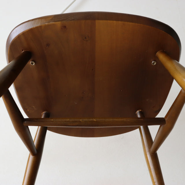Underside view of vintage British mid-century Ercol Quaker chair in warm teak, showcasing smooth wood grain and sturdy.