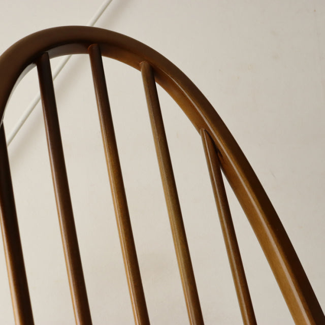 British mid-century Ercol Quaker chair in polished teak with curved spindle backrest and smooth wood grain finish.