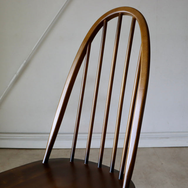 Vintage British mid-century ERCOL Quaker chair in polished teak with curved spindle back and smooth wood grain finish.