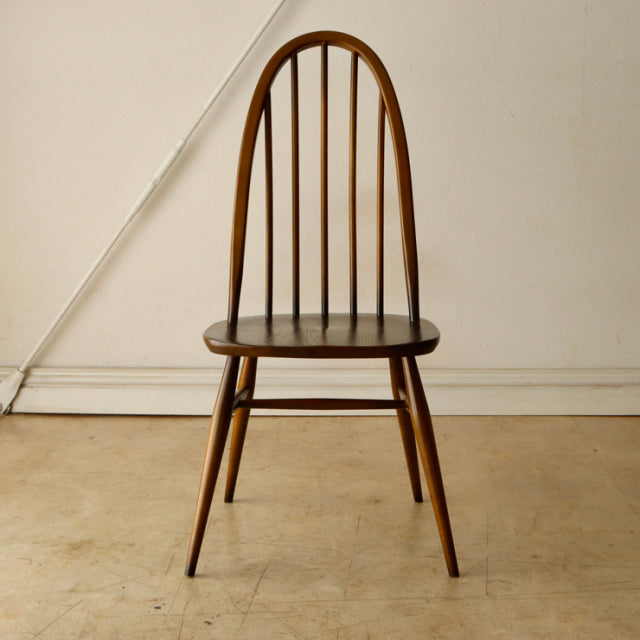 Vintage British mid-century Ercol Quaker chair in warm teak with a rounded spindle backrest and tapered legs.