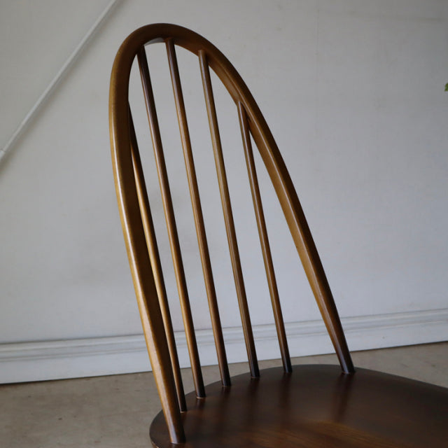 Vintage ERCOL Quaker dining chair in warm brown teak with a curved spindle backrest and tapered legs, showcasing mid-century .