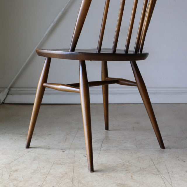 Vintage mid-century British Ercol Quaker chair in polished teak with slender, tapered legs and spindled backrest.