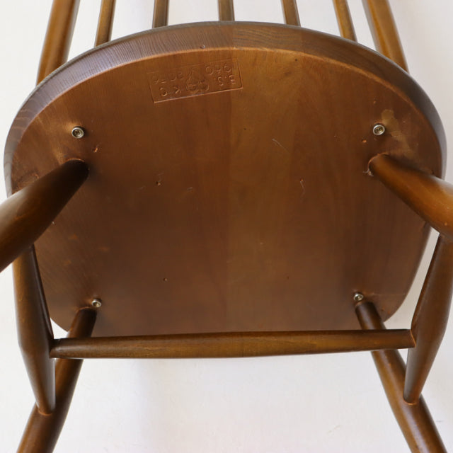 Underside view of vintage British Ercol Quaker chair in teak, showing wood grain, legs, and stamped brand logo in.