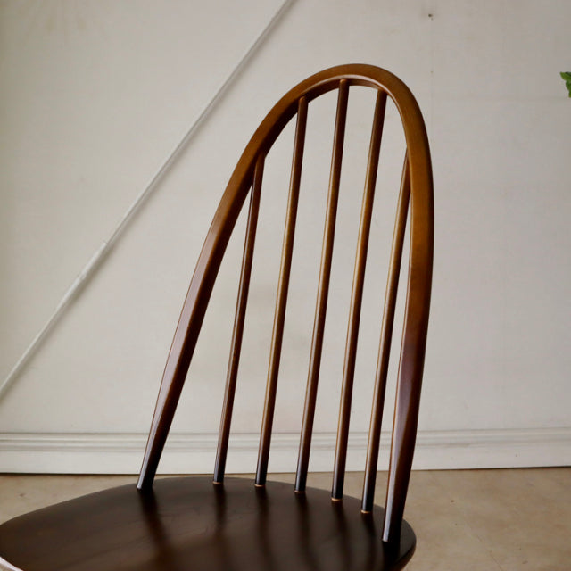 Vintage Ercol Quaker chair in warm teak with slender vertical spindles and curved mid-century British design.