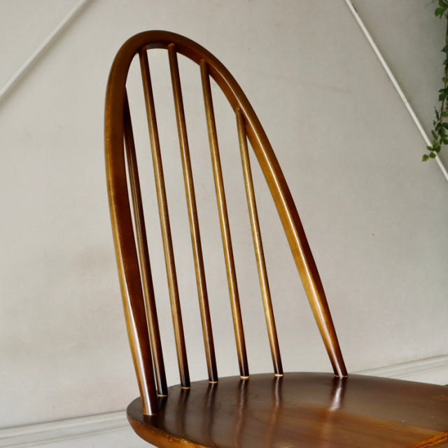 Vintage British mid-century ERCOL Quaker chair in polished teak with curved spindle back and smooth seat.