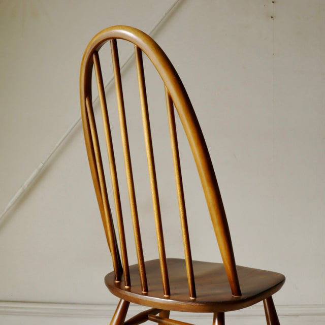 British mid-century ERCOL Quaker chair in warm brown teak wood with curved backrest and vertical spindles.