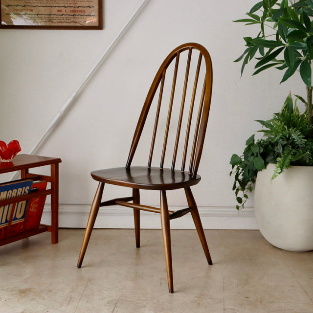 Mid-century British ERCOL Quaker chair in vintage teak with curved spindle back and tapered legs.