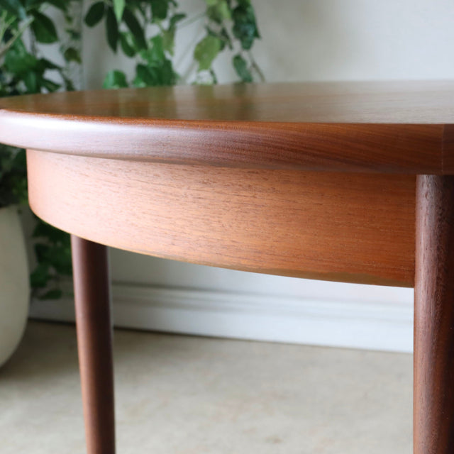 Vintage G-Plan teak dining table with rounded edges, smooth grain, and slender British mid-century legs in Denmark style.
