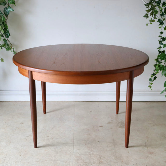 Vintage G-Plan teak dining table with smooth round top, tapered mid-century British legs, and warm wood grain from Denmark.