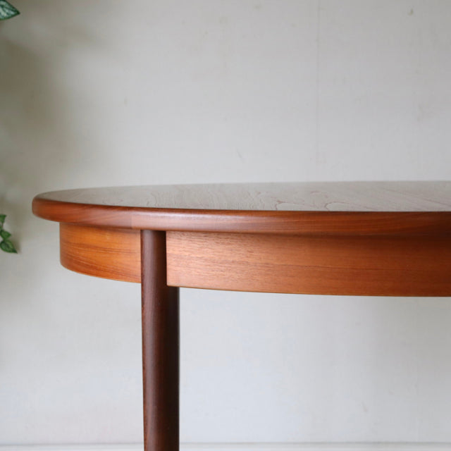 Vintage British mid-century G-Plan dining table in teak with rounded edge and slender tapered legs, smooth wood grain.