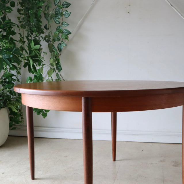 Vintage G-Plan mid-century teak dining table with oval top and tapered British-style legs, smooth wood grain finish.