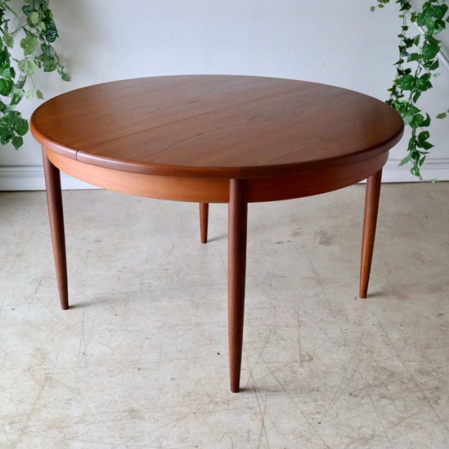 Vintage British G-Plan dining table in teak with smooth round top and tapered mid-century legs, Danish design influence.