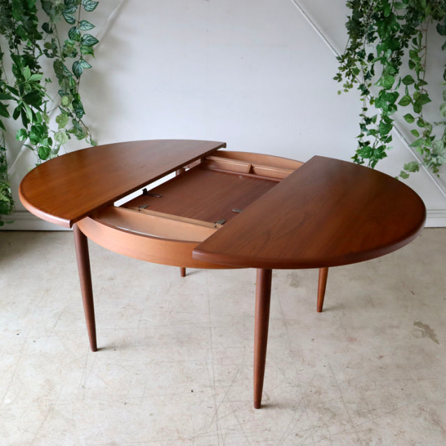 Mid-century British G-Plan dining table in vintage teak, oval shape with extendable leaf and tapered legs, showcasing rich.