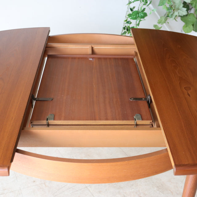 Mid-century British G-Plan vintage teak dining table with open butterfly extension and visible wood grain.
