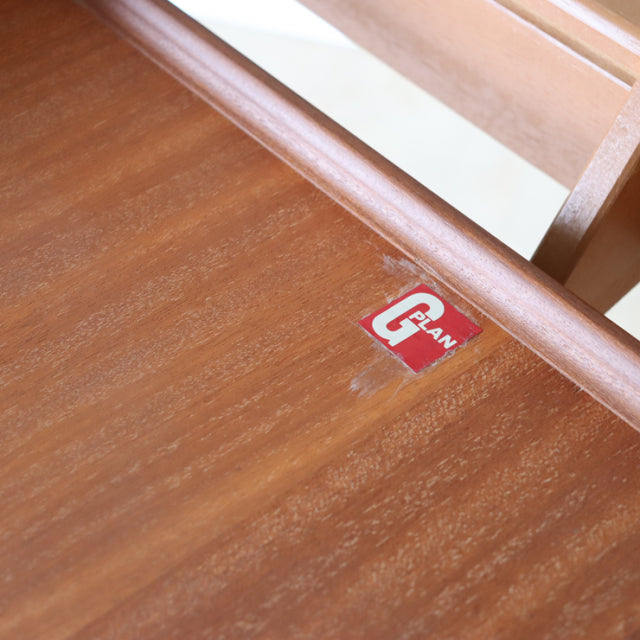 Close-up of vintage teak G-Plan dining table corner showing smooth wood grain and British mid-century design label.