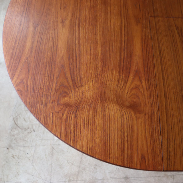 Round vintage teak dining table surface showing rich wood grain and smooth mid-century finish from British and Danish design .