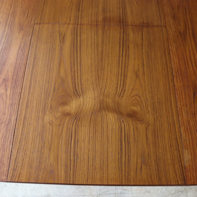 Vintage teak dining table top with rich wood grain and warm mid-century British craftsmanship details.