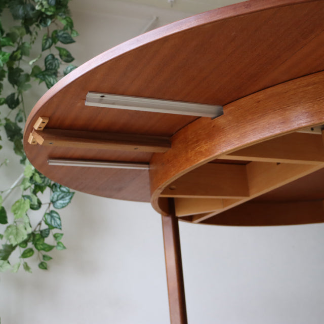 Vintage mid-century teak dining table with oval top, showcasing wood grain and sturdy British-Denmark design legs.